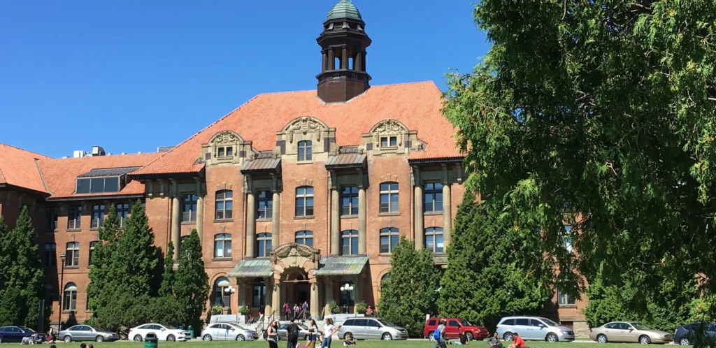 The main building of John Abbott College, a brick building with a clock tower, seen across the lawn in summer